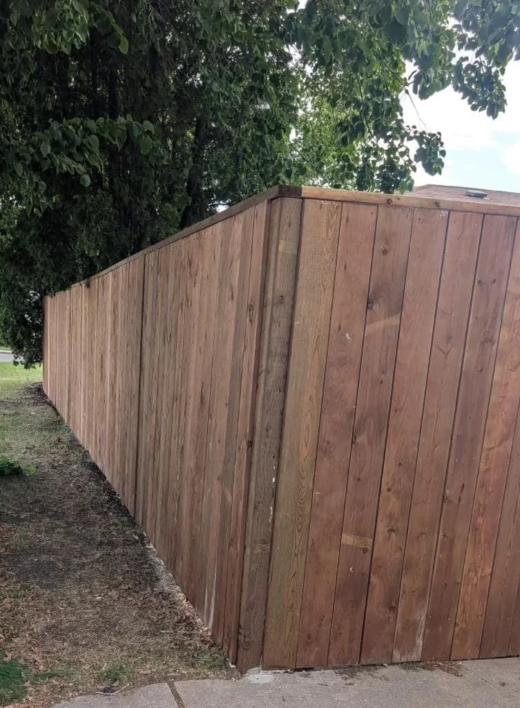 Completed vertical-board wood fence viewed from the property edge