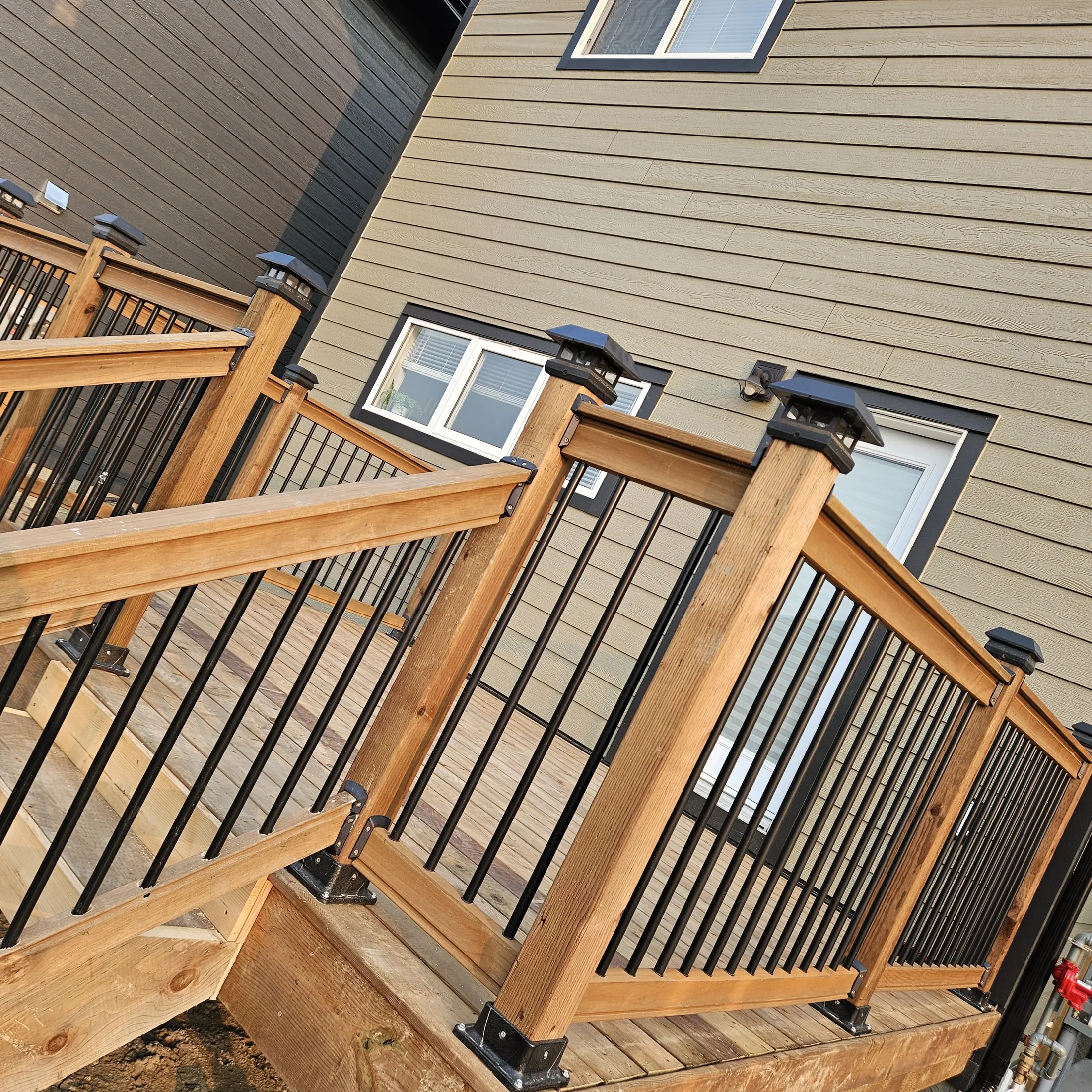 Wood deck railings with black balusters and integrated post lights