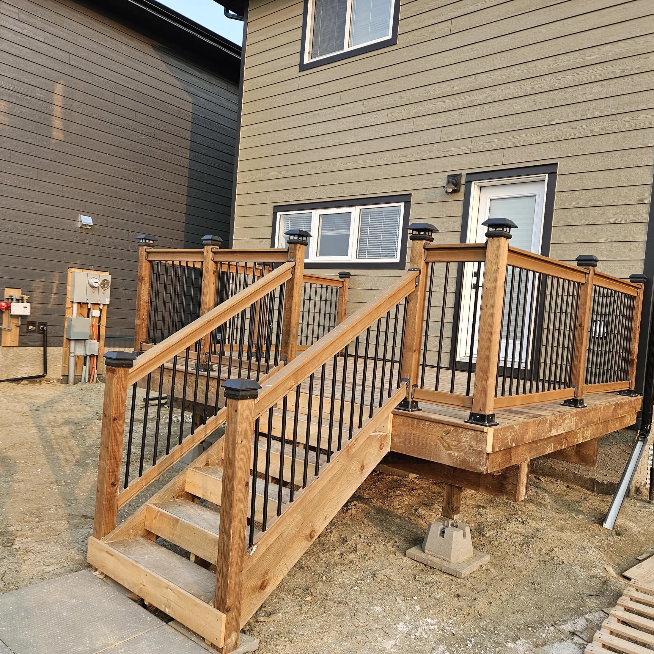 Completed wood deck with broad stairs and black aluminum railings at a Rosewood home